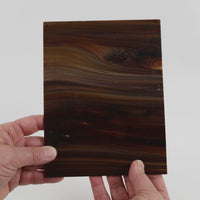 Video of the Nutmeg Streaky glass plate in opaque brown, 15x19cm, held up and tilted to show its pattern and transparency