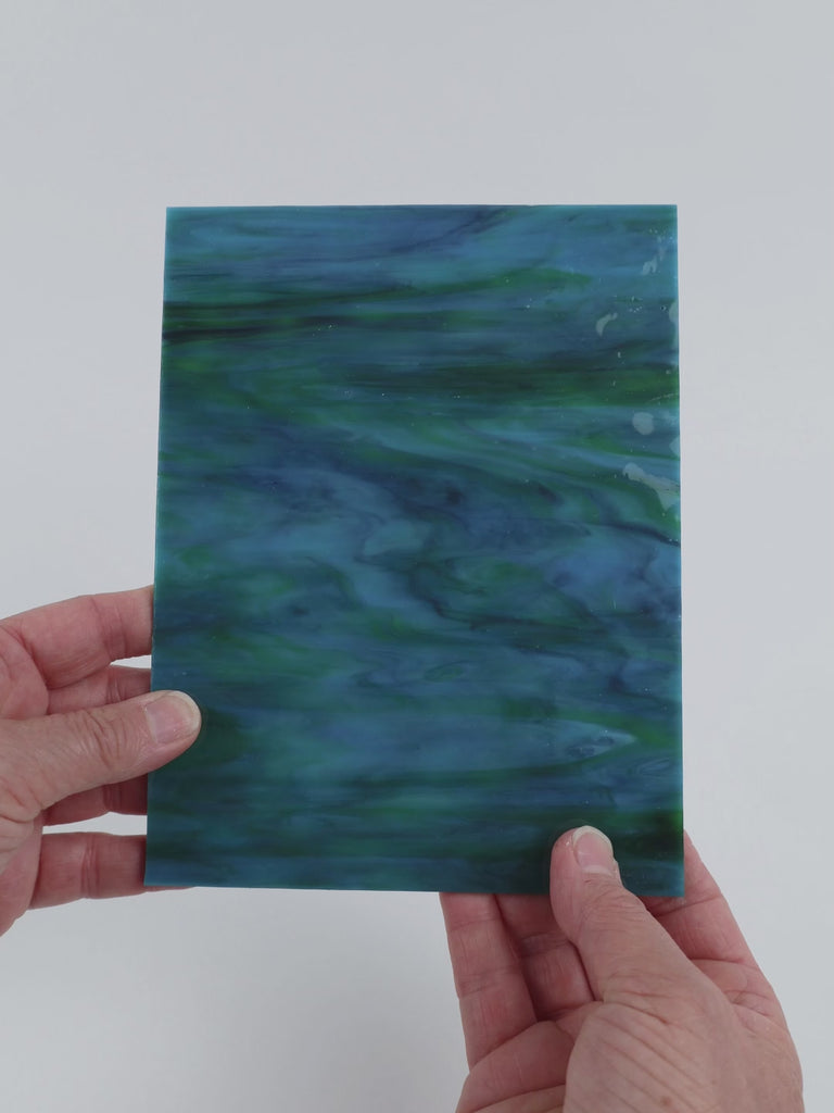 Video of the Peacock Gloss glass plate in ripple translucent teal, 15x19cm, held up and tilted to show its pattern and transparency