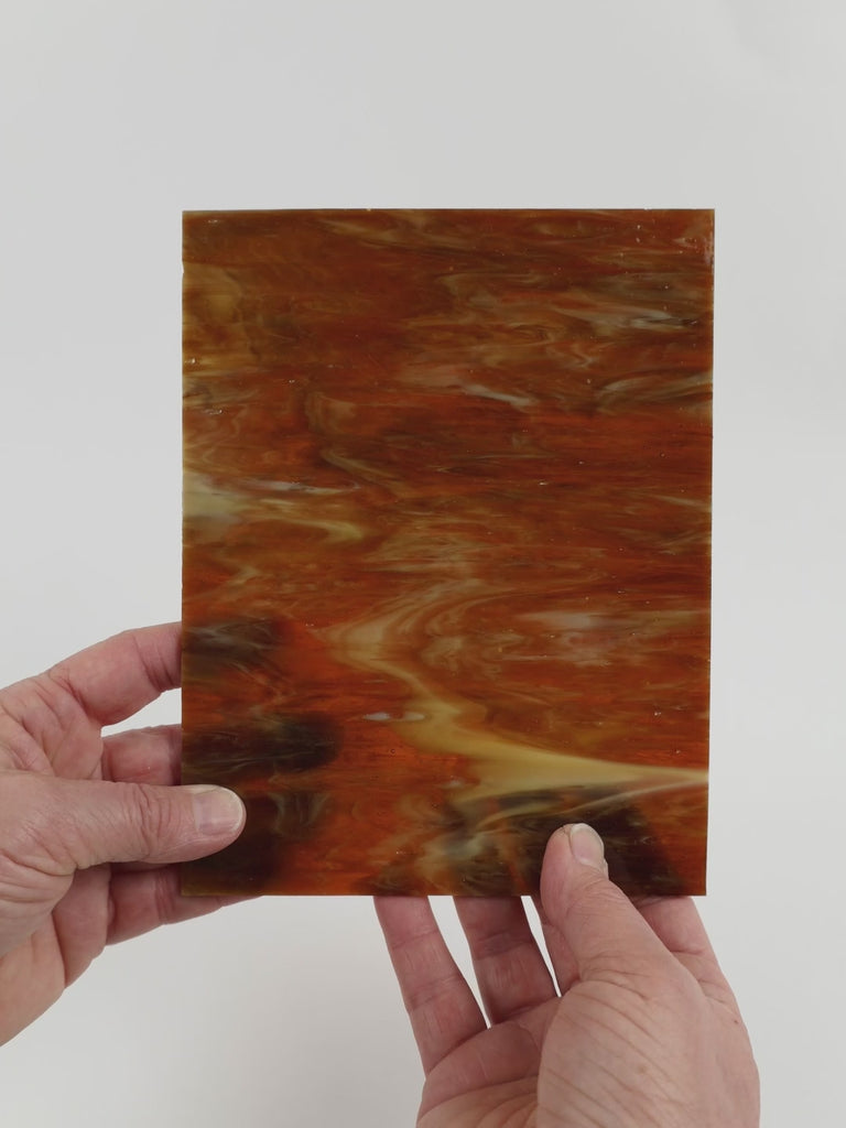 Video of the Syrup glass plate in translucent brown, 15x19cm, held up and tilted to show its pattern and transparency