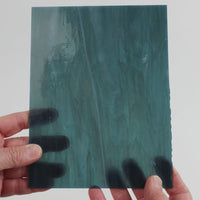 Video of the petrol grey glass plate in grey translucent marbled, 15x19cm, held up and tilted to show its pattern and transparency